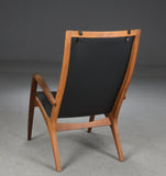 Jacob Berg.Walnut Armchair with ottoman, upholstered in black leather.