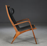 Jacob Berg.Walnut Armchair with ottoman, upholstered in black leather.