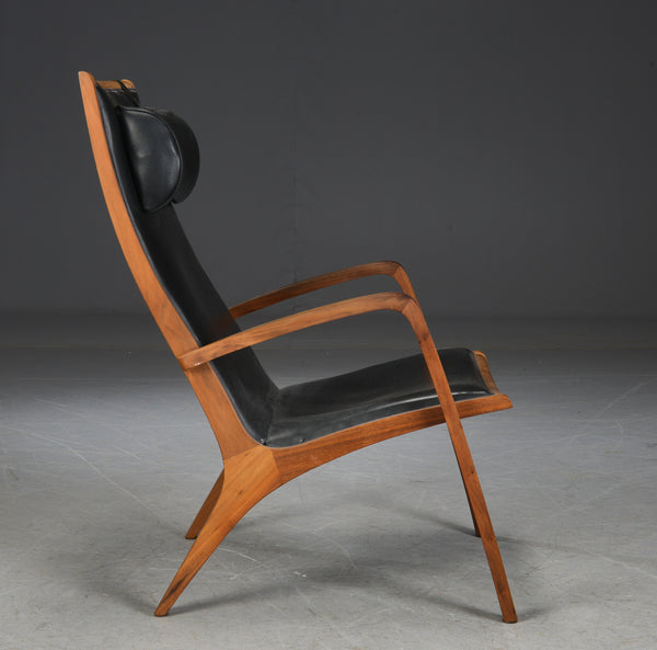 Jacob Berg.Walnut Armchair with ottoman, upholstered in black leather.