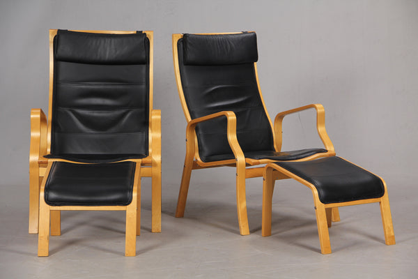 Two Sets of Black Leather Beech Armchairs and Footstools